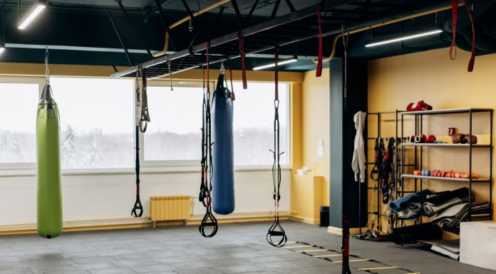 A modern gym with equipment, punching bags, and open space for workouts.