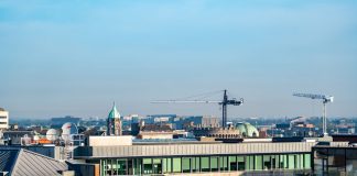 A vibrant view of Dublin's cityscape featuring construction cranes and iconic architecture under a clear blue sky.