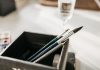 Detailed image of paintbrushes and pencil in a holder with soft light.