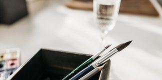Detailed image of paintbrushes and pencil in a holder with soft light.