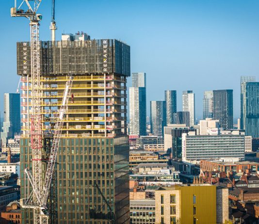 Aerial view of modern skyscrapers in Manchester with ongoing construction highlighting urban growth.