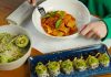 Delicious pasta with fresh basil and avocado salad served in an inviting setting. Perfect for health-conscious diners.