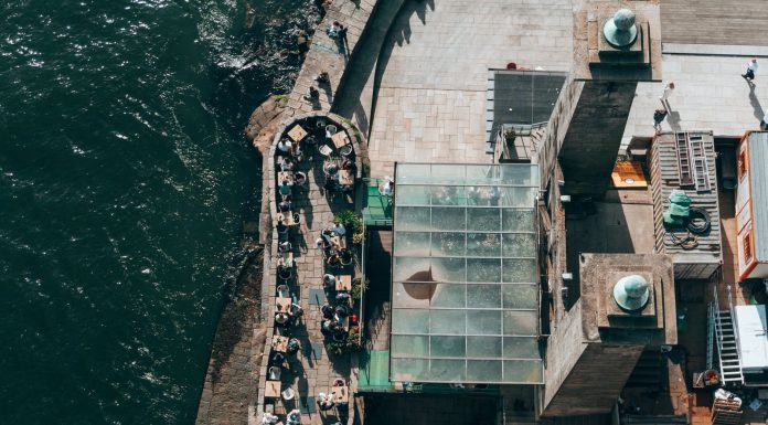 ÚLTIMA HORA: Nuevo restaurante COV abre en la costa de Edgewater Top-down view of a riverside restaurant in Porto, Portugal, with people dining outdoors.