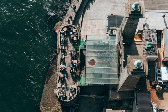 Top-down view of a riverside restaurant in Porto, Portugal, with people dining outdoors.