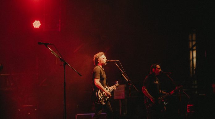 ÚLTIMA HORA: Super Trans AM se presenta en concierto en Bayonne Live rock band performing on stage with vibrant red lighting creating a dynamic atmosphere.