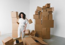 ÚLTIMA HORA: Washington General Store se muda a nuevo local en Hoboken Young female with curly hair between piles and flying cardboard containers after moving into house on light background