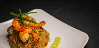Savory prawn fried rice garnished with chives on a stylish white plate, capturing gourmet cuisine.