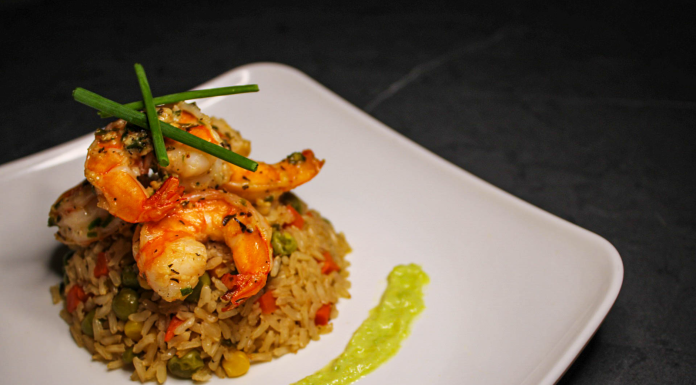 Savory prawn fried rice garnished with chives on a stylish white plate, capturing gourmet cuisine.