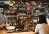 Bartender mixing a cocktail for a customer in a trendy urban bar with extensive liquor collection.