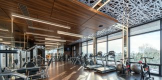 Los Mejores Gimnasios en Hoboken para Todo Presupuesto (2026) Modern exercise bikes and treadmills and various fitness equipment in spacious gym with wooden floor and panoramic windows in sunlight