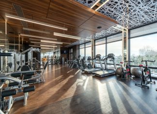 Los Mejores Gimnasios en Hoboken para Todo Presupuesto (2026) Modern exercise bikes and treadmills and various fitness equipment in spacious gym with wooden floor and panoramic windows in sunlight