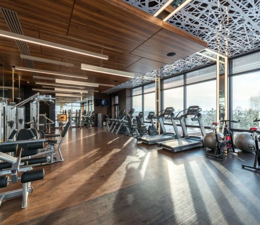 Los Mejores Gimnasios en Hoboken para Todo Presupuesto (2026) Modern exercise bikes and treadmills and various fitness equipment in spacious gym with wooden floor and panoramic windows in sunlight