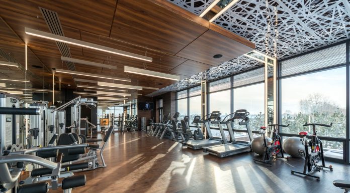 Los Mejores Gimnasios en Hoboken para Todo Presupuesto (2026) Modern exercise bikes and treadmills and various fitness equipment in spacious gym with wooden floor and panoramic windows in sunlight