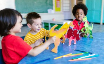 Los Mejores Jardines de Infancia en Hoboken: Guía Completa para Padres en 2026 Three kids playing with dinosaur figures, fostering imagination and learning.