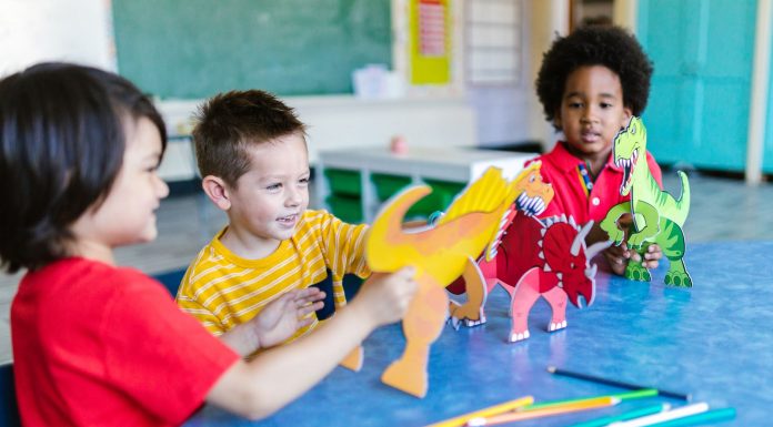 Los Mejores Jardines de Infancia en Hoboken: Guía Completa para Padres en 2026 Three kids playing with dinosaur figures, fostering imagination and learning.