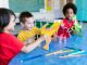 Los Mejores Jardines de Infancia en Hoboken: Guía Completa para Padres en 2026 Three kids playing with dinosaur figures, fostering imagination and learning.