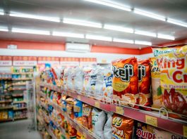Wide shot of vibrant snack aisle in a supermarket with various chip bags on display.