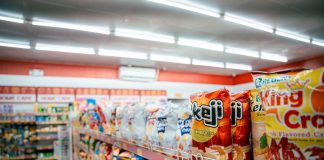 Wide shot of vibrant snack aisle in a supermarket with various chip bags on display.