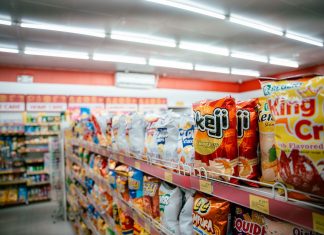 Wide shot of vibrant snack aisle in a supermarket with various chip bags on display.