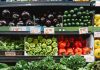 Colorful assortment of vegetables on display in a supermarket, featuring peppers, eggplants, and squash.