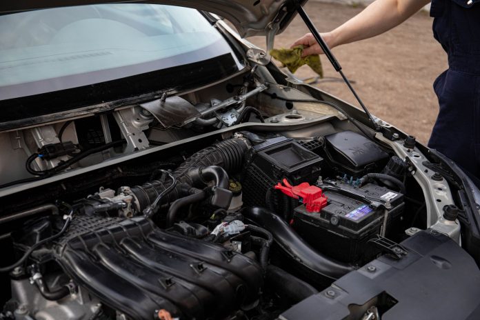 mejores-talleres-mecanicos-north-bergen Mechanic inspecting car engine bay and battery during routine maintenance.