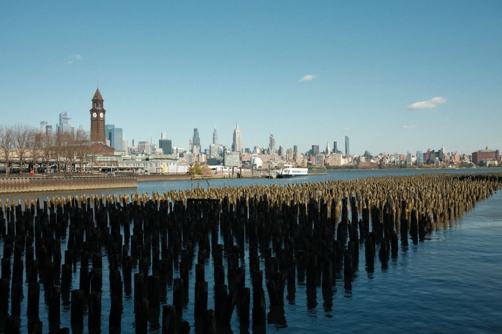Scenic view of New York City skyline from Hoboken waterfront with wooden piers in the foreground.