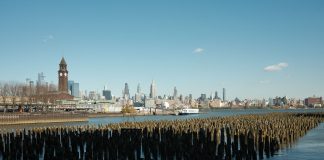 Scenic view of New York City skyline from Hoboken waterfront with wooden piers in the foreground.