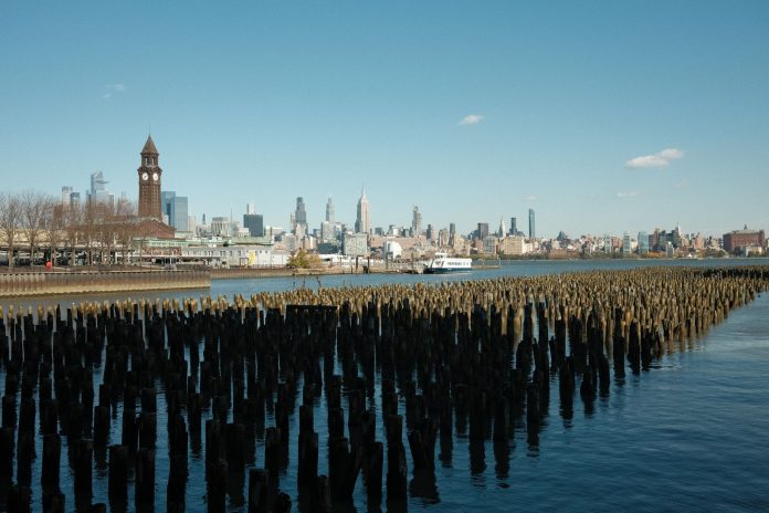 Scenic view of New York City skyline from Hoboken waterfront with wooden piers in the foreground.