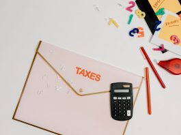 Flat lay of a tax preparation workspace with calculator, envelope, and colorful numbers.