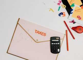 Flat lay of a tax preparation workspace with calculator, envelope, and colorful numbers.