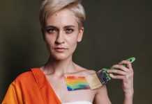 A woman displays LGBTQ pride with rainbow colors painted on her shoulder.