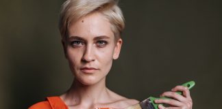A woman displays LGBTQ pride with rainbow colors painted on her shoulder.