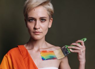 A woman displays LGBTQ pride with rainbow colors painted on her shoulder.