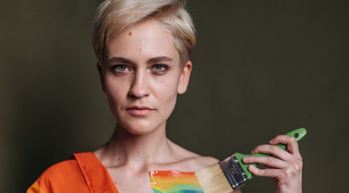 A woman displays LGBTQ pride with rainbow colors painted on her shoulder.