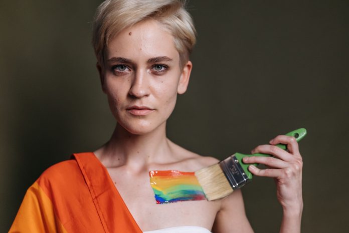 A woman displays LGBTQ pride with rainbow colors painted on her shoulder.