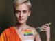 A woman displays LGBTQ pride with rainbow colors painted on her shoulder.