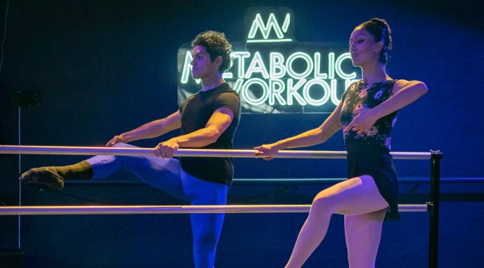 Pure Barre Brings Low-Impact Strength to Hudson County Two ballet dancers practice at a barre under a neon sign in an indoor studio.