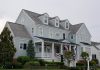 Elegant colonial-style house in Cape May, NJ with manicured lawn and American flags.