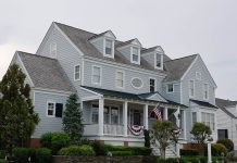 Elegant colonial-style house in Cape May, NJ with manicured lawn and American flags.