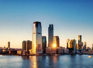 Breathtaking sunrise view over New York City skyline with reflection on the water.