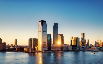 Breathtaking sunrise view over New York City skyline with reflection on the water.