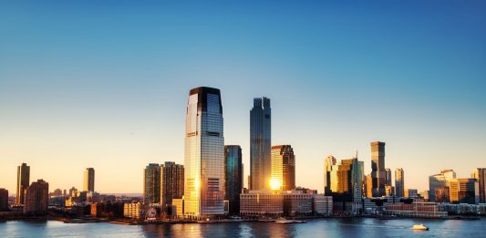 Breathtaking sunrise view over New York City skyline with reflection on the water.