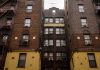 Low-angle view of urban brick apartment buildings with fire escapes, embodying classic city architecture.