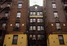 Low-angle view of urban brick apartment buildings with fire escapes, embodying classic city architecture.