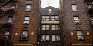 Low-angle view of urban brick apartment buildings with fire escapes, embodying classic city architecture.