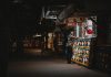 A vibrant night scene capturing an interaction at a street food stall with illuminated menus.