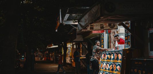 Restaurants Open Late in Jersey City: Your 2026 Late-Night Dining Guide A vibrant night scene capturing an interaction at a street food stall with illuminated menus.
