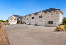 A modern suburban residential building featuring a large driveway under a clear blue sky.
