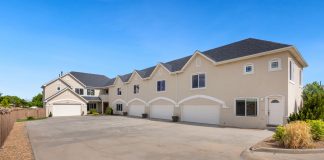 A modern suburban residential building featuring a large driveway under a clear blue sky.