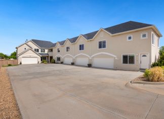 A modern suburban residential building featuring a large driveway under a clear blue sky.